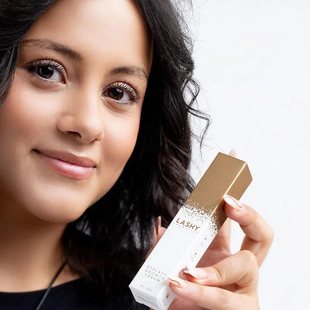 Close-up of a happy Lashy Cosmetics model showcasing the Lashy eyelash serum box, with bright eyes reflecting enhanced lash growth results.