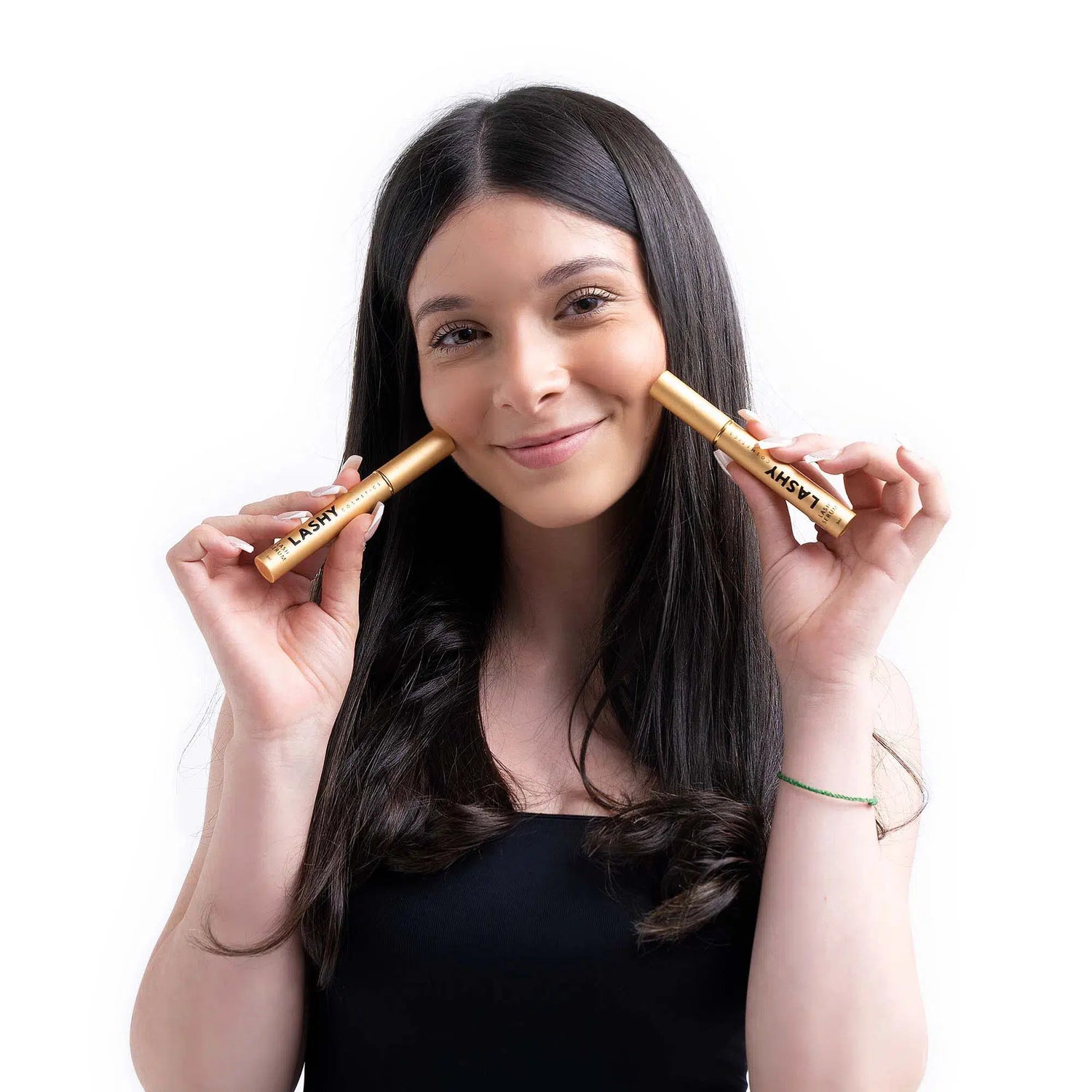 Half-body view of a Lashy Cosmetics model holding two bottles of Lashy eyelash serum with a gentle smile.
