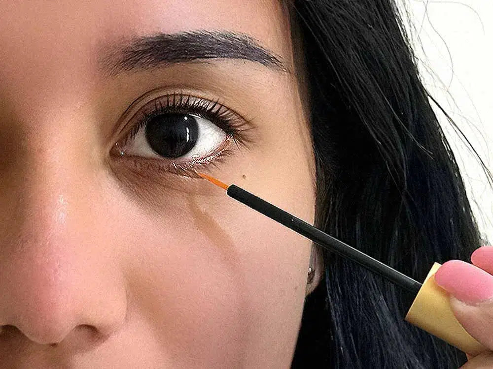Close-up of a Lashy Cosmetics model's left eye, demonstrating how to apply eyelash growth serum to her lower lashes with precision for lash enhancement.